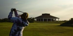 man in blue jacket playing golf during daytime