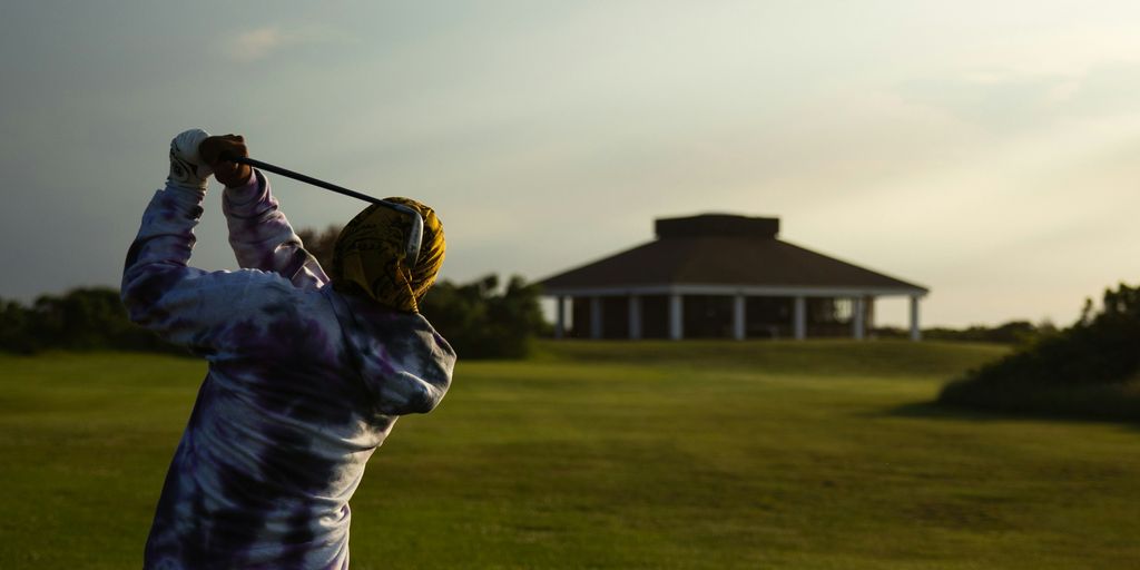 man in blue jacket playing golf during daytime