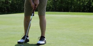 man in brown shorts and black nike shoes playing golf during daytime