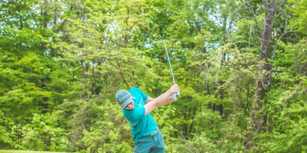 man playing golf near green trees during daytime