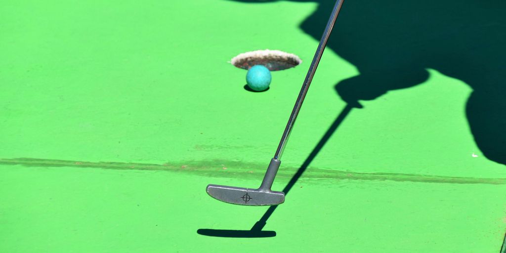 person golfing and ball about to shoot in hole